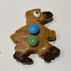 Das Bild zeigt einen Lebkuchen in Form von Detektiv Dachs mit zwei Smarties und Schokofüssen