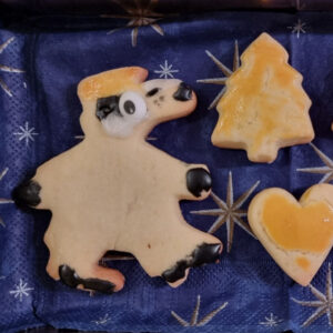 Auf dem Bild sieht mein ein Weihnachtsguetzli in Form eines Detektiv Dachs. Neben dran hat es ein Mailänderli in Tannenform und herzform.